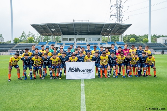 Group photo of male players standing shoulder to shoulder on the grass of a soccer field